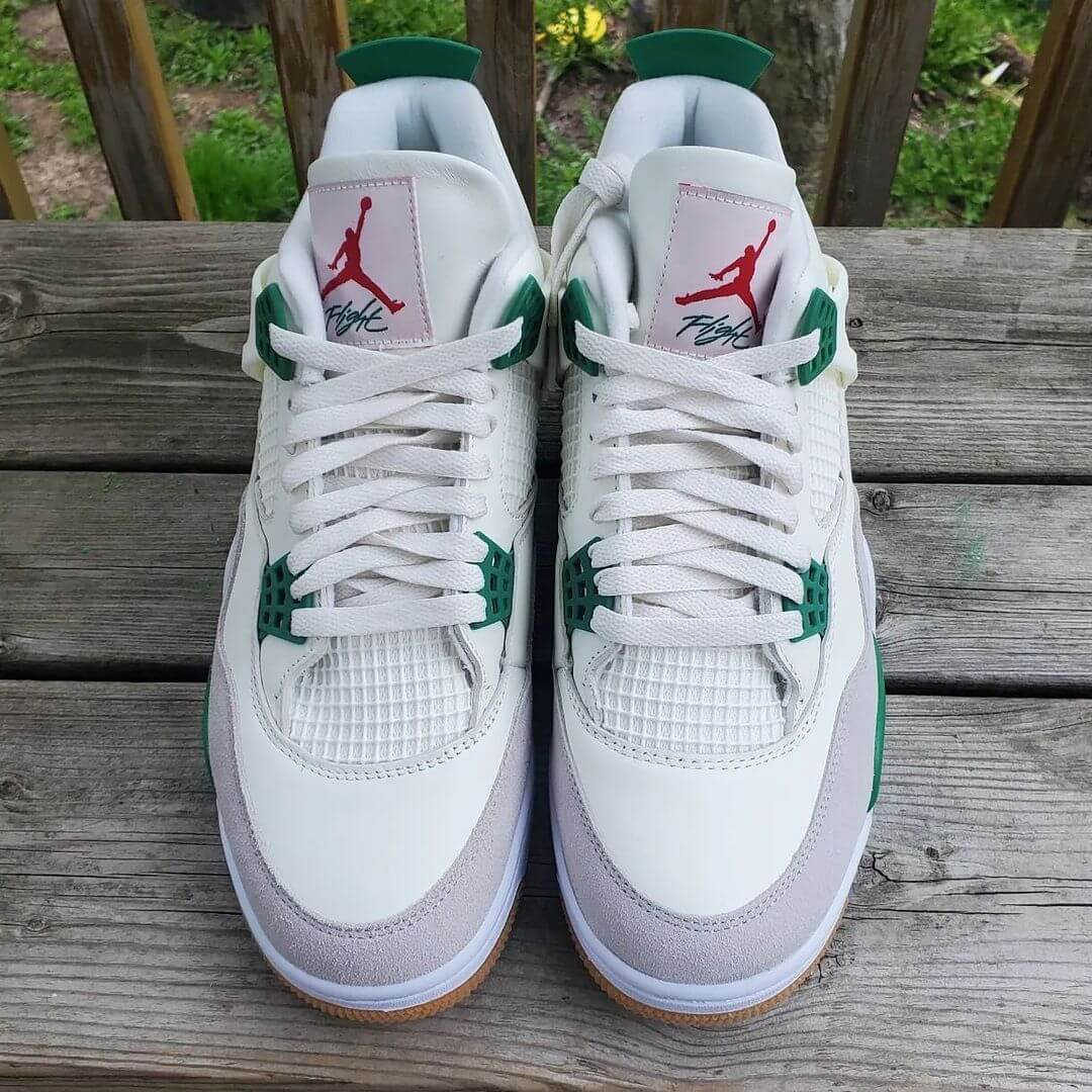 A pair of Air Jordan 4 Retro "Pine Green" sneakers with white leather, grey suede, and pine green accents.