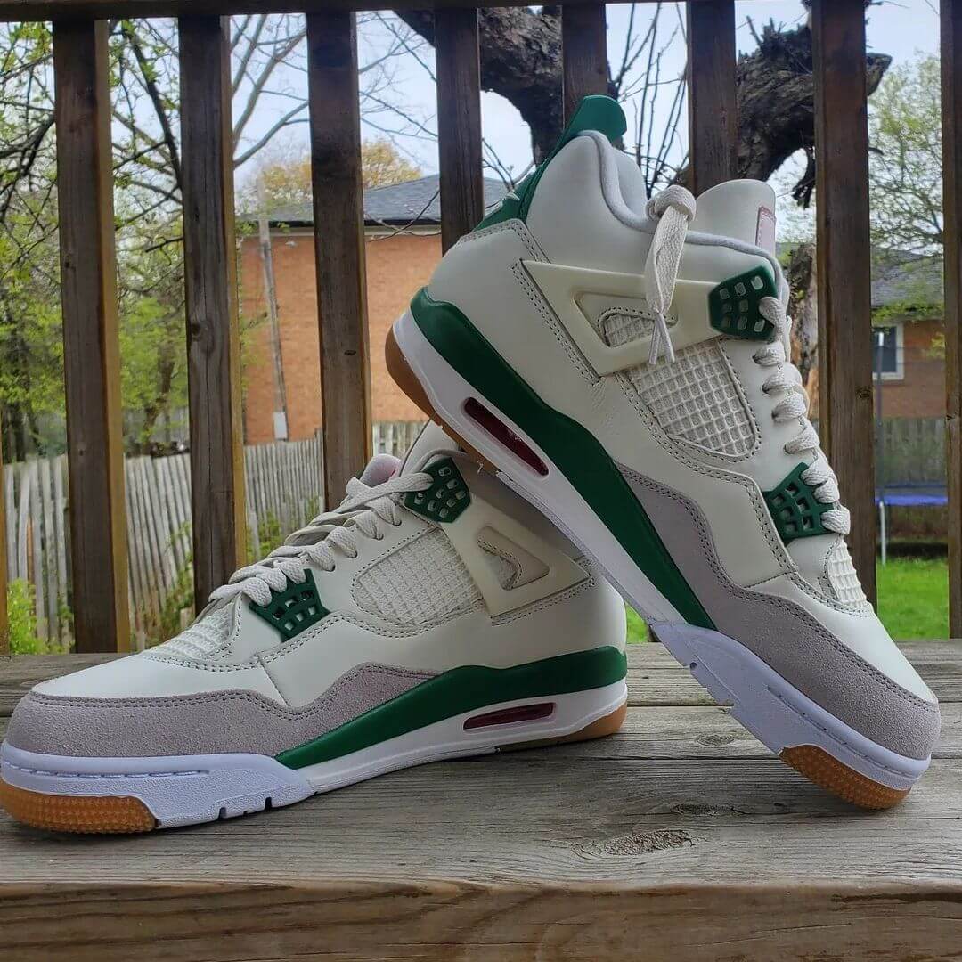 A pair of Air Jordan 4 Retro "Pine Green" sneakers with white leather, grey suede, and pine green accents.