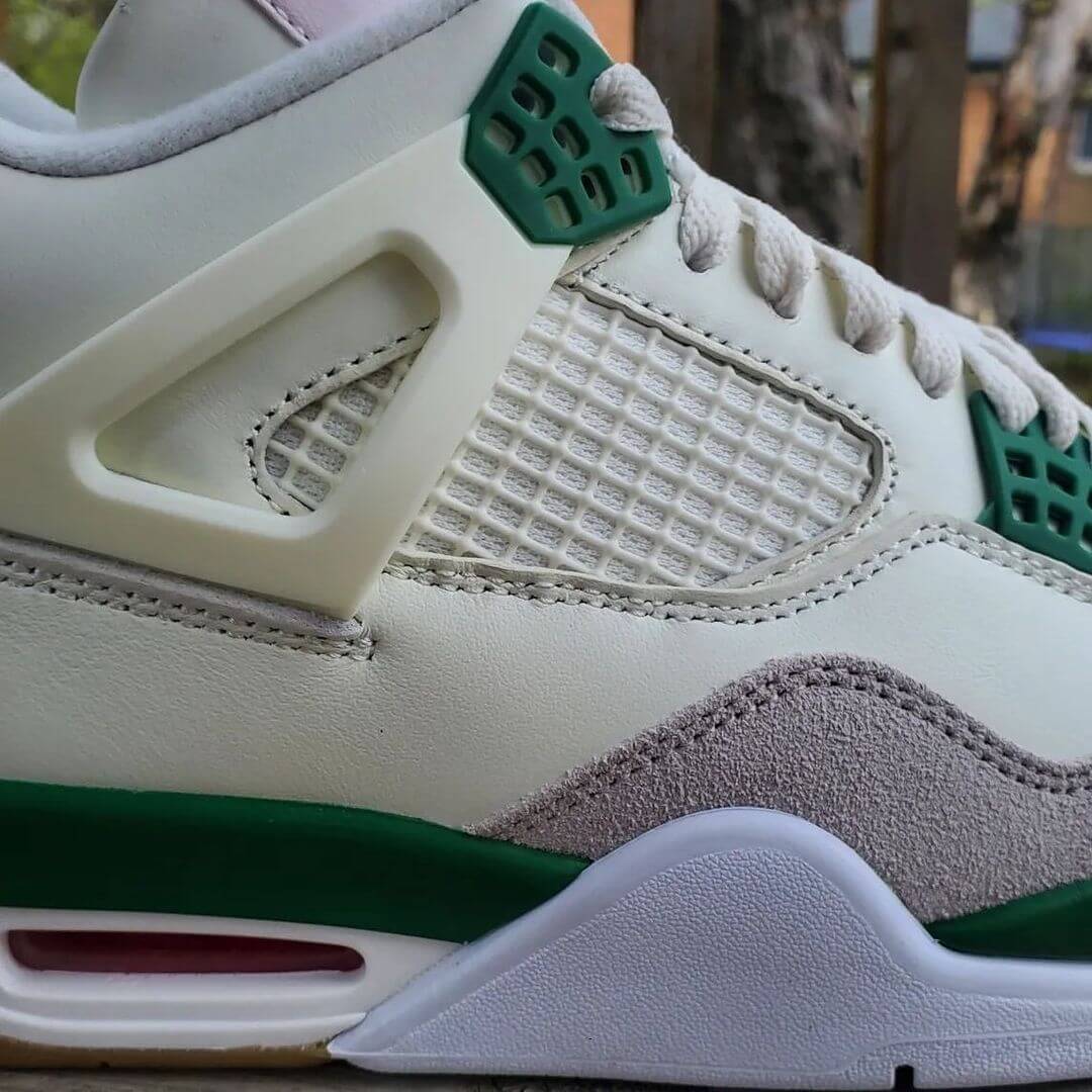 A pair of Air Jordan 4 Retro "Pine Green" sneakers with white leather, grey suede, and pine green accents.