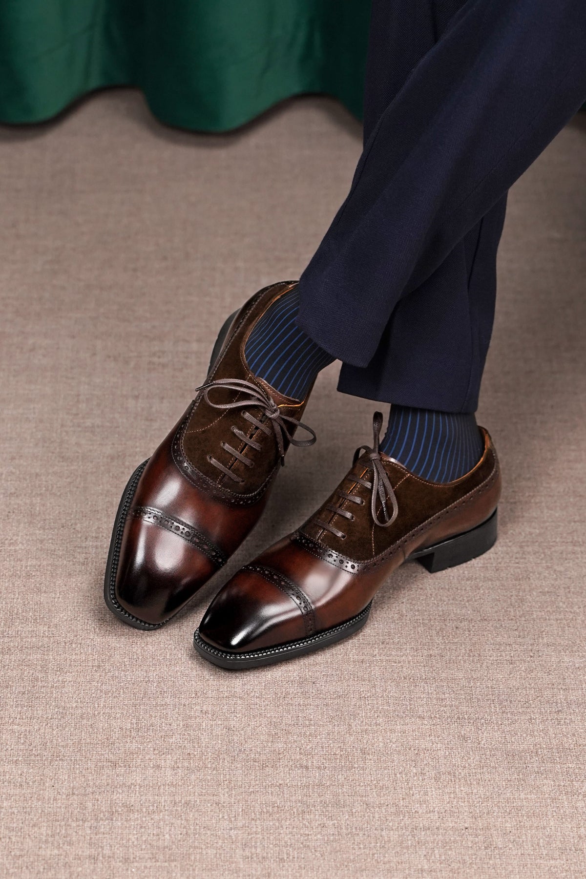 Brown dress shoes with navy socks on a beige carpet