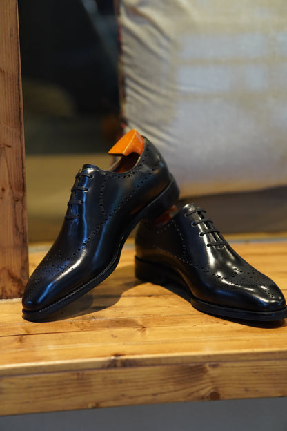 Black Oxford shoes with classic brogue detailing and a sleek, polished finish