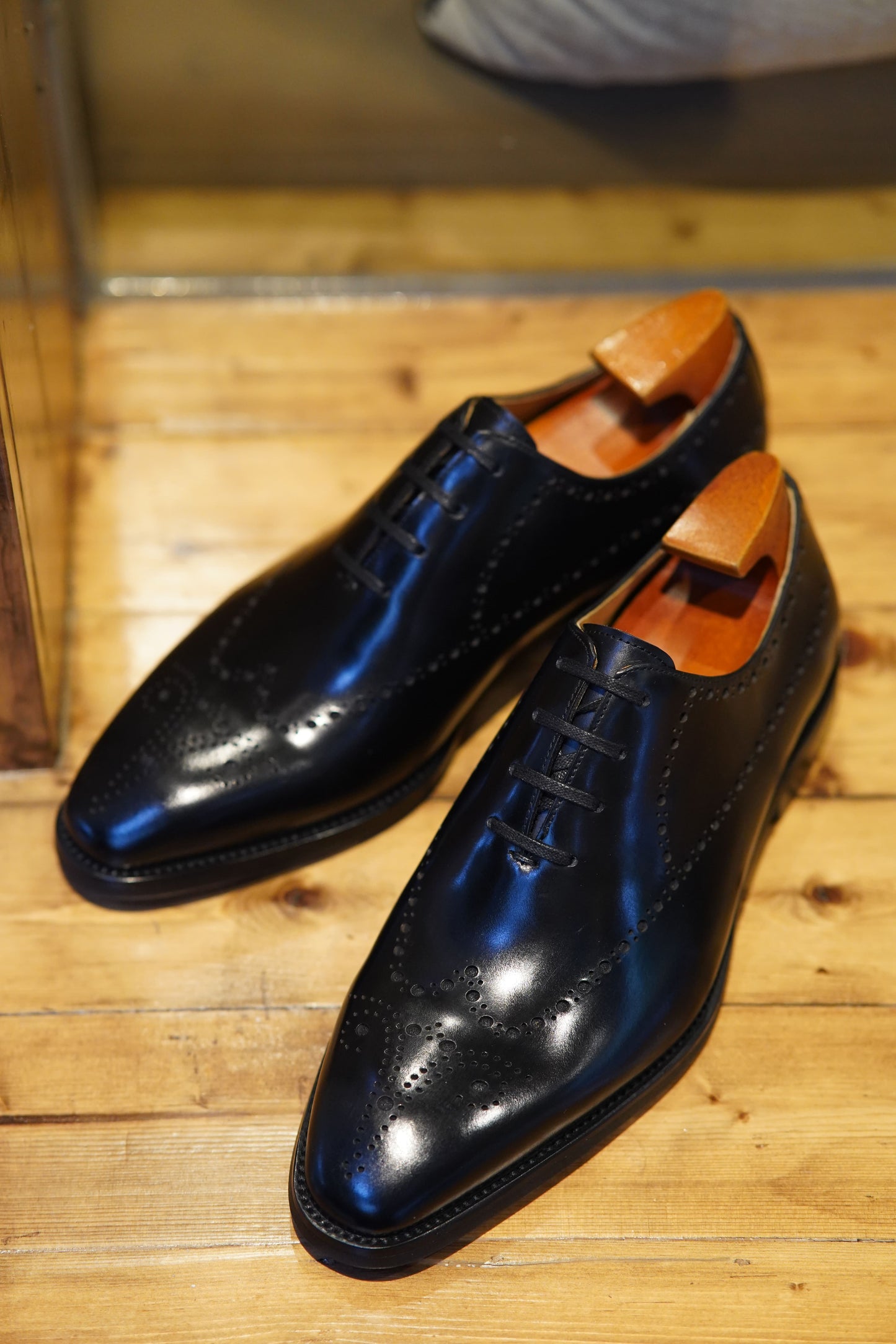 Men's formal footwear: Black Oxford shoes with classic brogue detailing and a sleek, polished finish