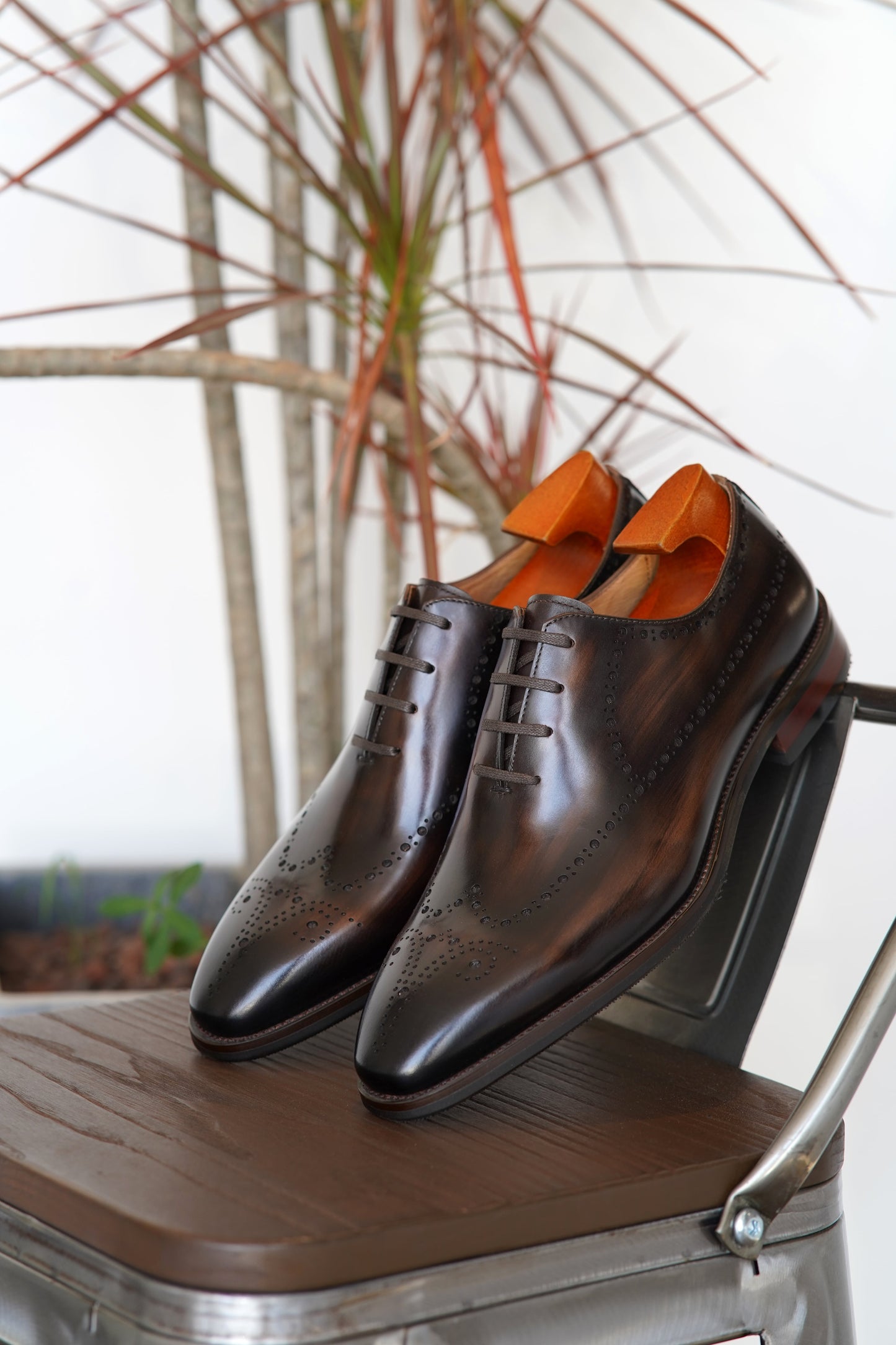 Pair of men's brown burnished calfskin Oxford shoes with brogue detailing.