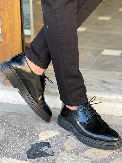 Black Derby Lace-Up Shoes – sleek black leather, worn by a man in black trousers, walking on patterned ground, ideal for versatile everyday style.