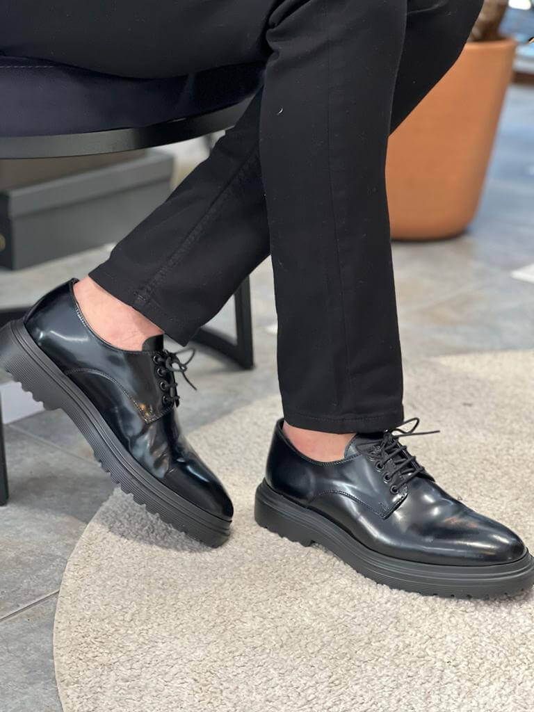 Black Derby Lace-Up Shoes – comfortable polished leather, worn by a man in black trousers, standing on steps, highlighting sleek design for everyday wear.