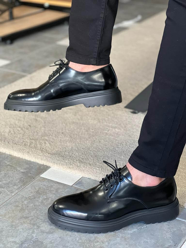 Black Derby Lace-Up Shoes – sleek black leather, worn by a man in black trousers, casually seated, highlighting polished finish and comfortable EVA sole.