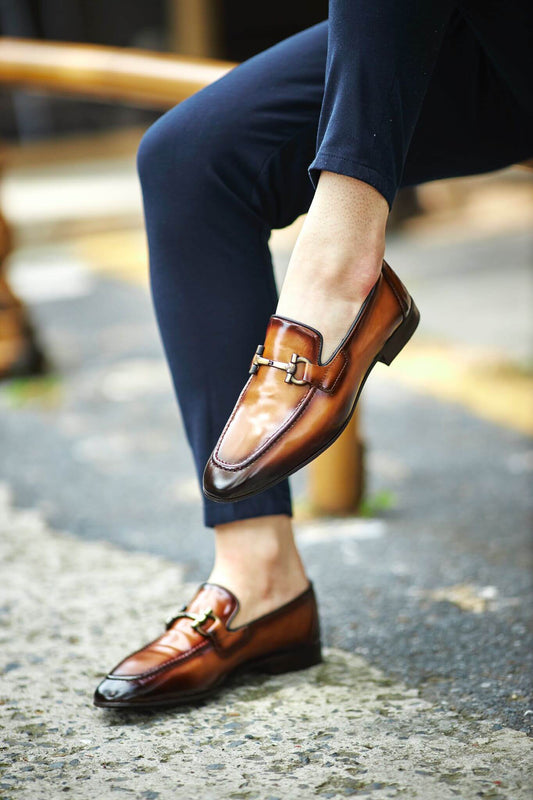 Custer Camel Bit Loafers – Classic Leather Footwear for Every Occasion – worn by a man in dark trousers, sitting, highlighting a sleek silhouette and polished finish with a classic horsebit buckle.