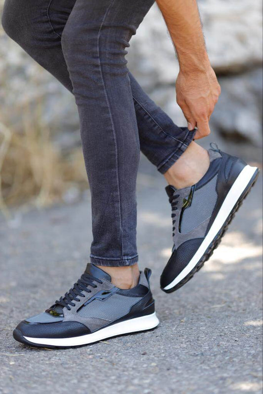 Detailed Gray Sneakers for Casual & Everyday Wear – worn by a man in grey jeans, adjusting his trouser cuff, highlighting patent leather and a sleek silhouette.