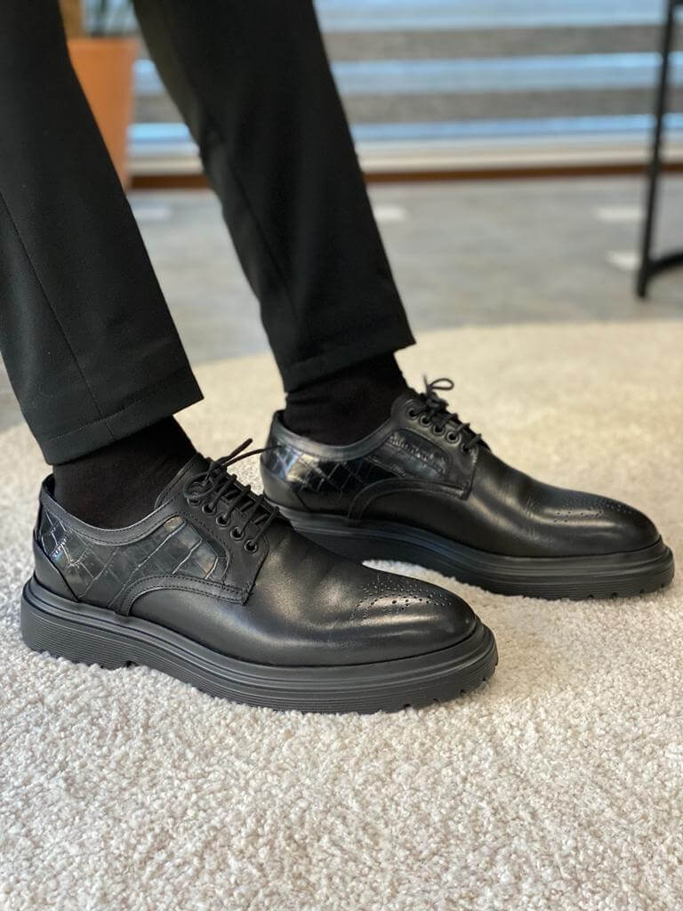 Handcrafted Black Leather Derby Shoes – sleek black leather, worn by a man in black trousers with one foot lifted, highlighting the EVA sole and versatile style.