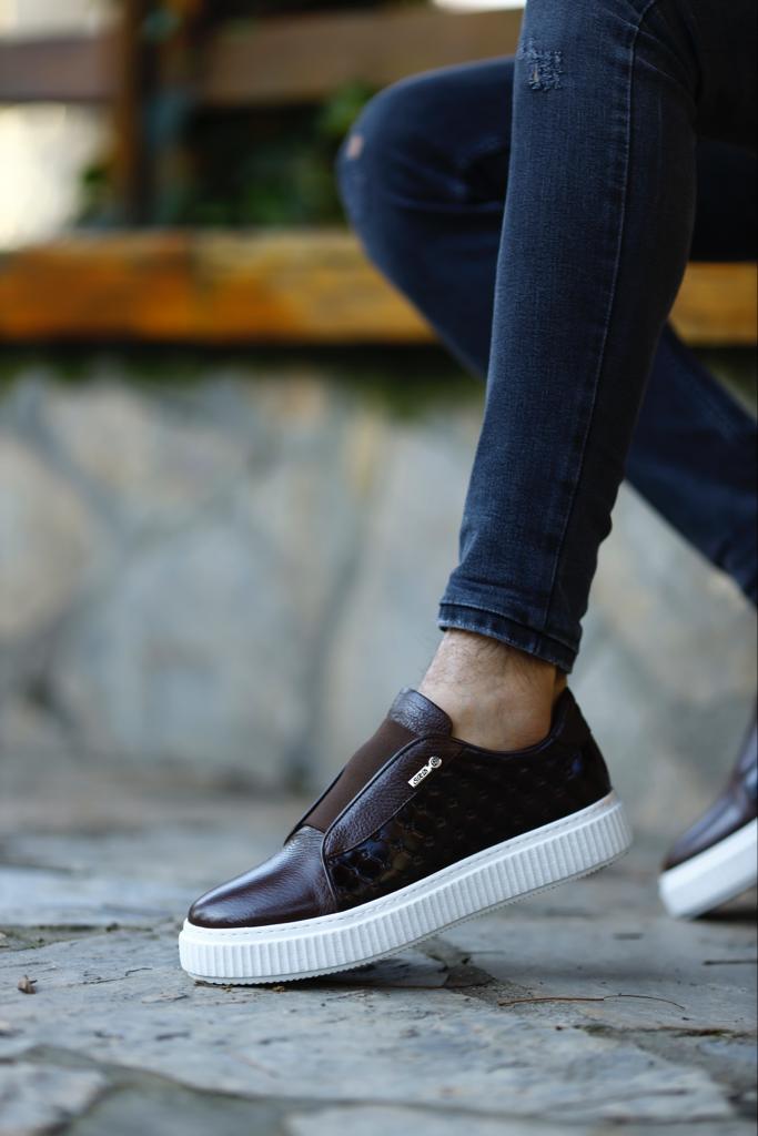 Handcrafted Vortex Brown Float Leather Slip-Ons – worn by a man with one foot elevated, showcasing a blend of traditional craftsmanship and modern innovation.