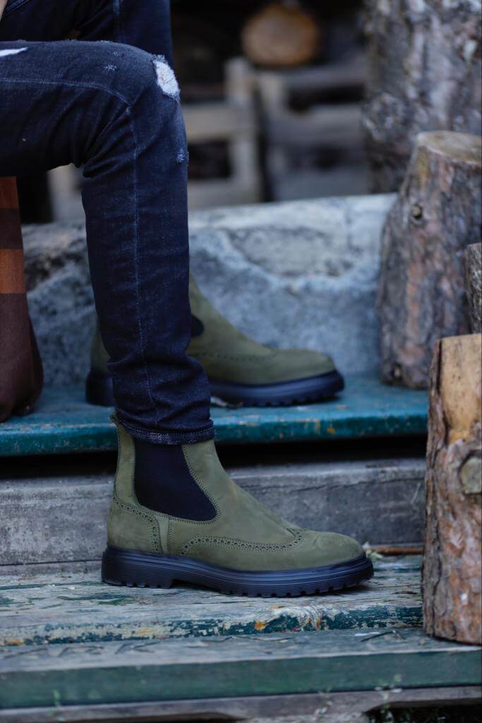 HolloShoe Khaki Nubuck Wingtip Chelsea Boots for All-Day Comfort – a man wearing the khaki nubuck boots with distressed denim and one foot resting on a log, showing the tread.