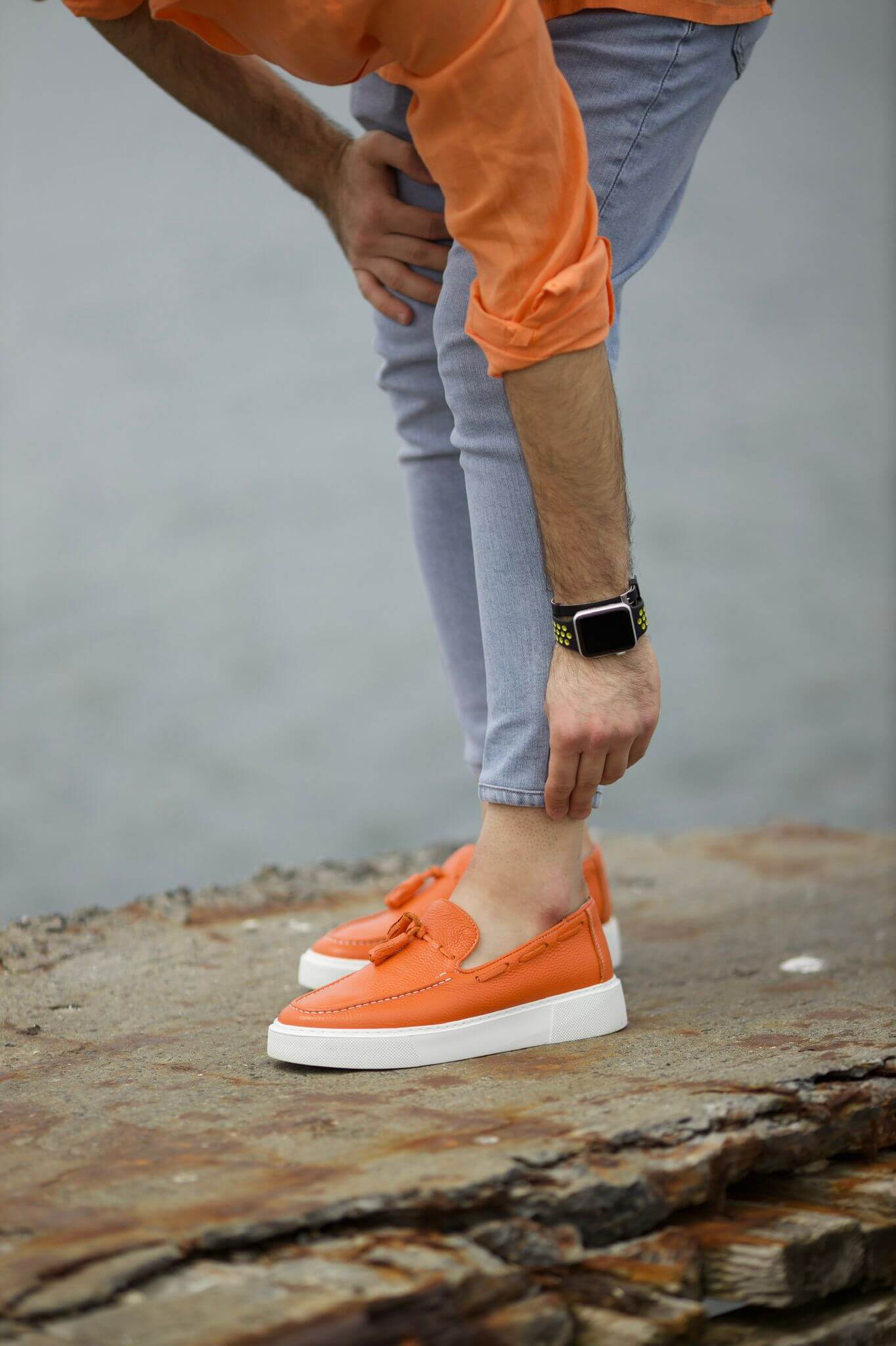 A Orange Tassel Leather Slip Ons on display.