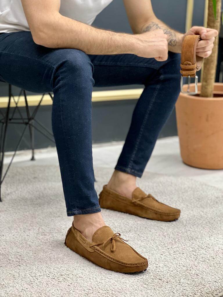 Premium Oakmond Brown Suede Driving Loafers – man holding a matching brown leather belt while wearing the shoes.