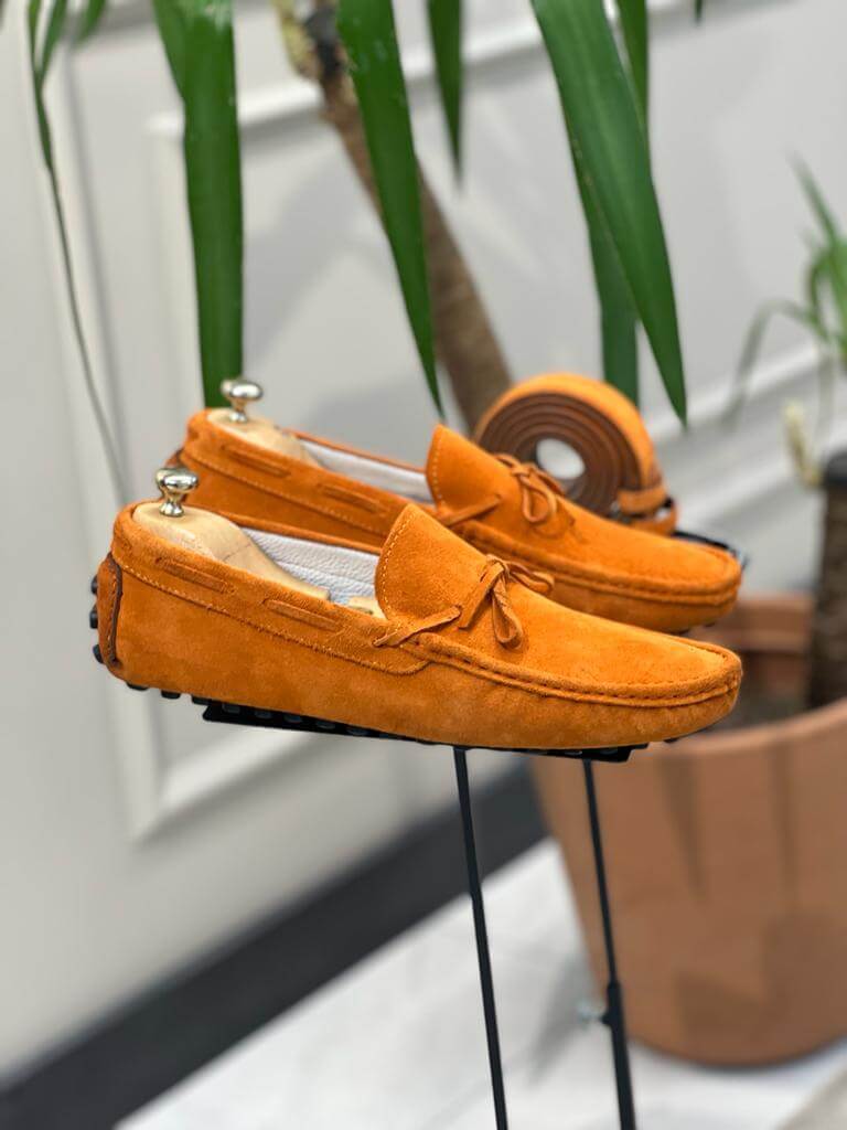 Premium Oakmond Orange Suede Driving Loafers – pair displayed on a stand, with a matching belt, highlighting a luxurious touch and comfortable fit.