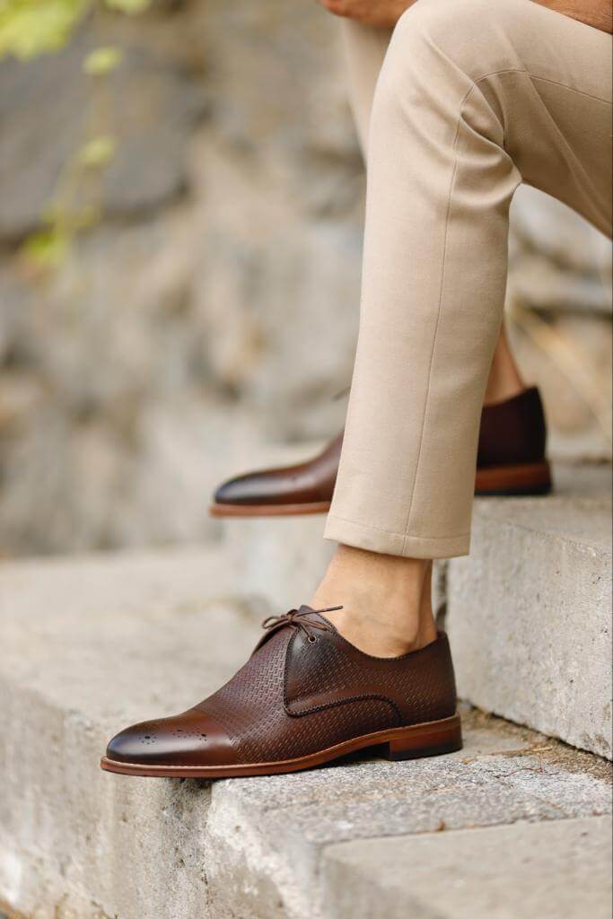 Unique Design Brown Leather Lace-Up Shoes – rich brown genuine leather, worn by a man in beige chinos, standing on a textured path, for versatile style.