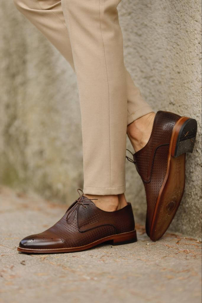 Unique Design Brown Leather Lace-Up Shoes – rich brown genuine leather, worn by a man in beige chinos, standing on a textured path, for versatile style.