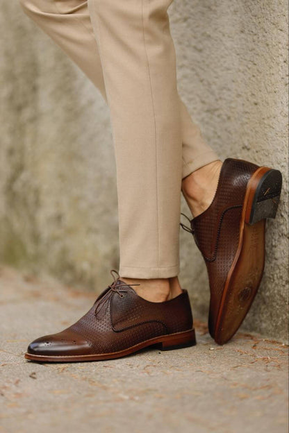 Unique Design Brown Leather Lace-Up Shoes – rich brown genuine leather, worn by a man in beige chinos, standing on a textured path, for versatile style.