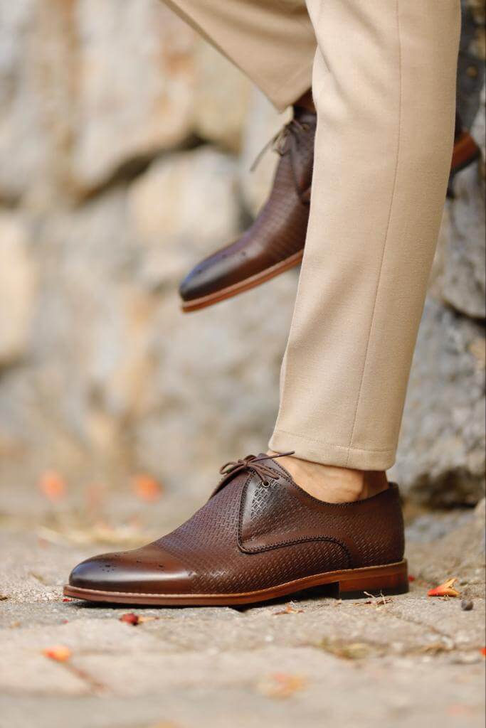 Unique Design Brown Leather Lace-Up Shoes – rich brown genuine leather, worn by a man in beige chinos, standing on a textured path, for versatile style.